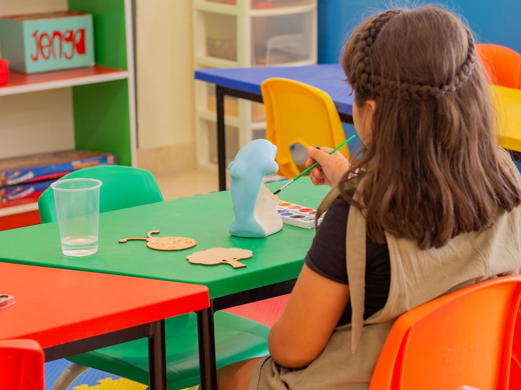 A girl painting a dolphin statue in play area at Plaza Pelicanos Grand Beach Resort