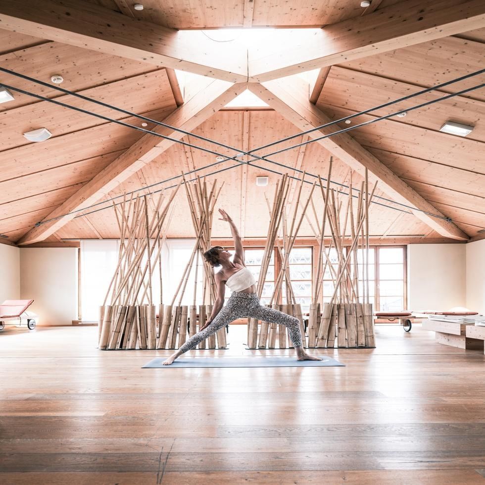 Frau in Yogahaltung in einem hellen Raum mit Holzelementen und Bambusinstallationen während der Clubwoche ACTIVE.