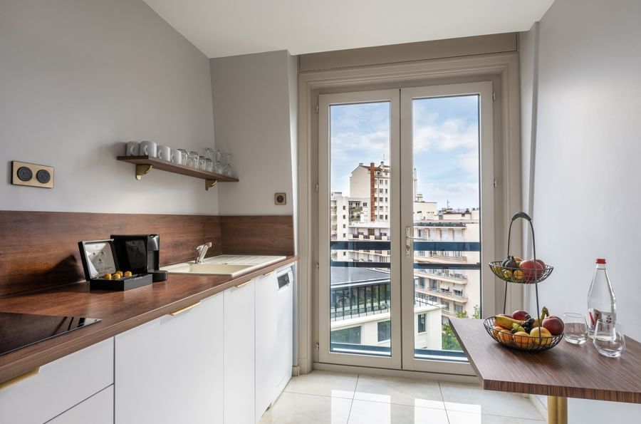 Modern kitchen corner with white cabinets and wooden countertops in the Privilege Suite at Warwick Reine Astrid - Lyon