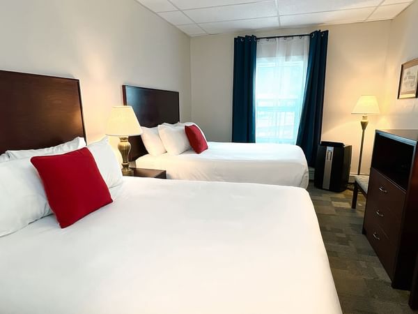 Hotel bedroom with two queen beds, tv, chair, mirror, and lamp
