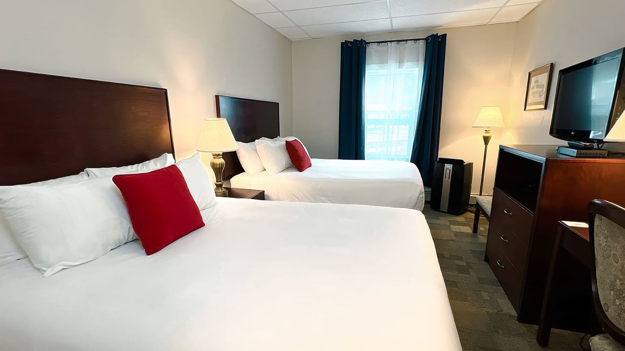 Hotel bedroom with two queen beds, tv, chair, mirror, and lamp