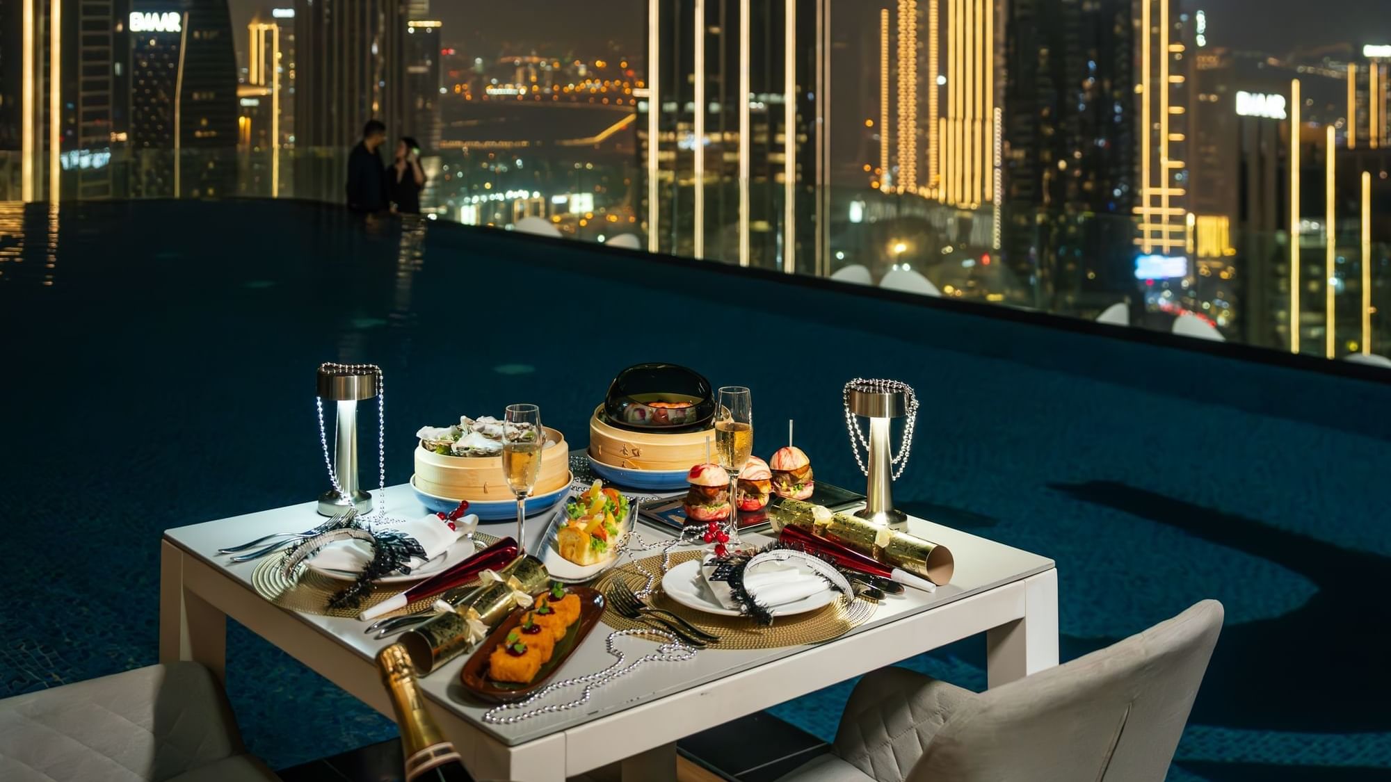Romantic dinner setting by an infinity pool with a stunning nighttime cityscape view at Paramount Hotel Midtown