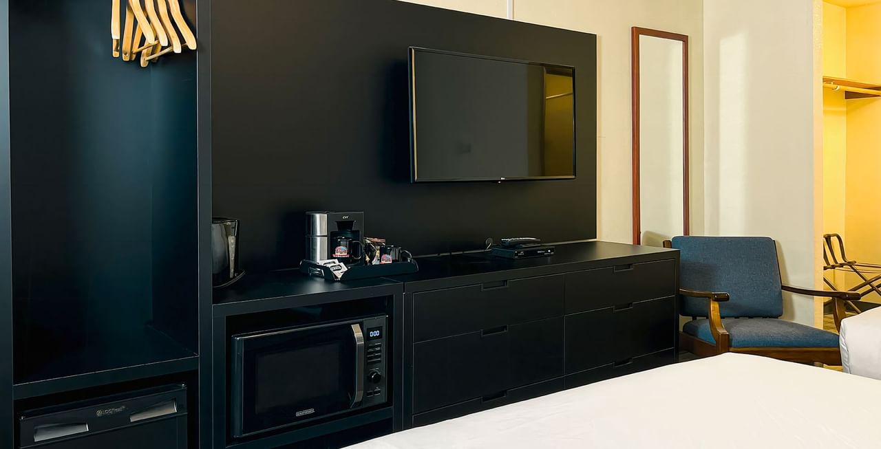 Hotel room with beds, TV, microwave, coffee maker, chair, and clothing hangers