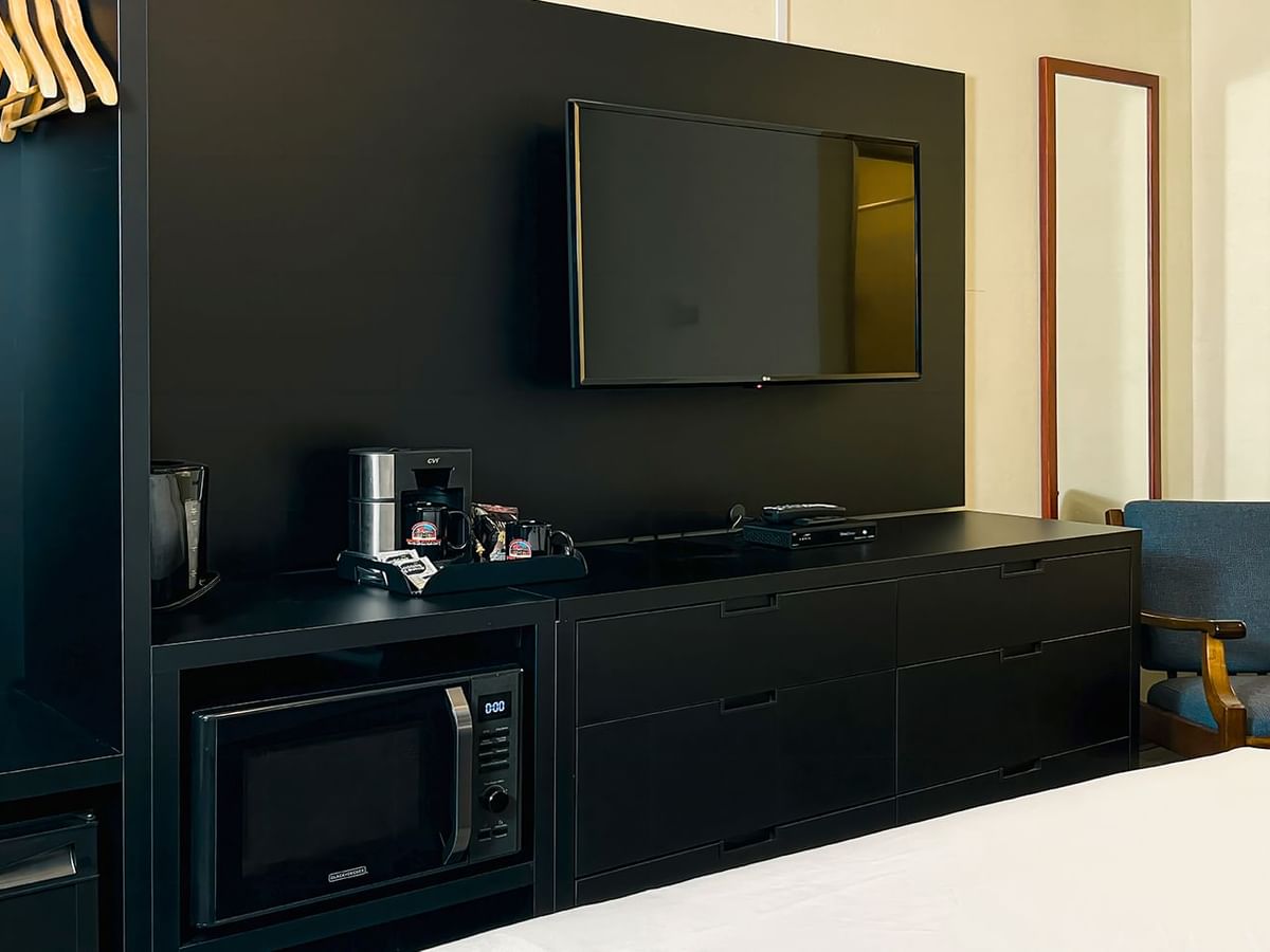 Room with closer, microwave, TV, mirror, bed, chair, and coffee maker