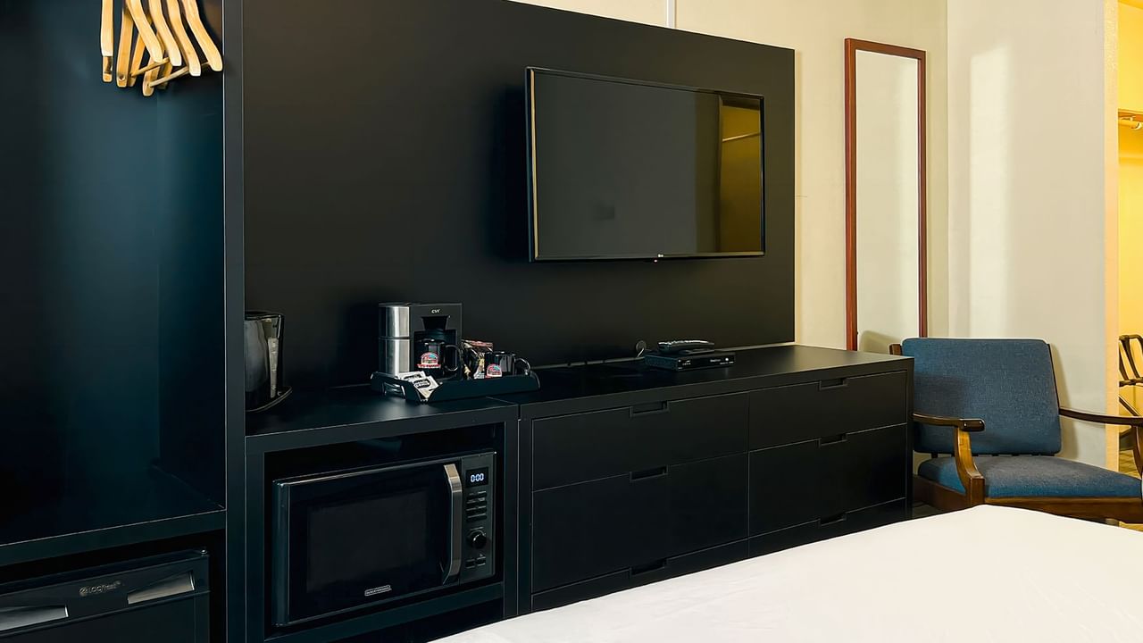 Room with closer, microwave, TV, mirror, bed, chair, and coffee maker