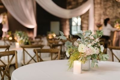 Wedding reception table centerpiece with candles, white and pink flowers, and eucalyptus at Centennial Plaza Resort