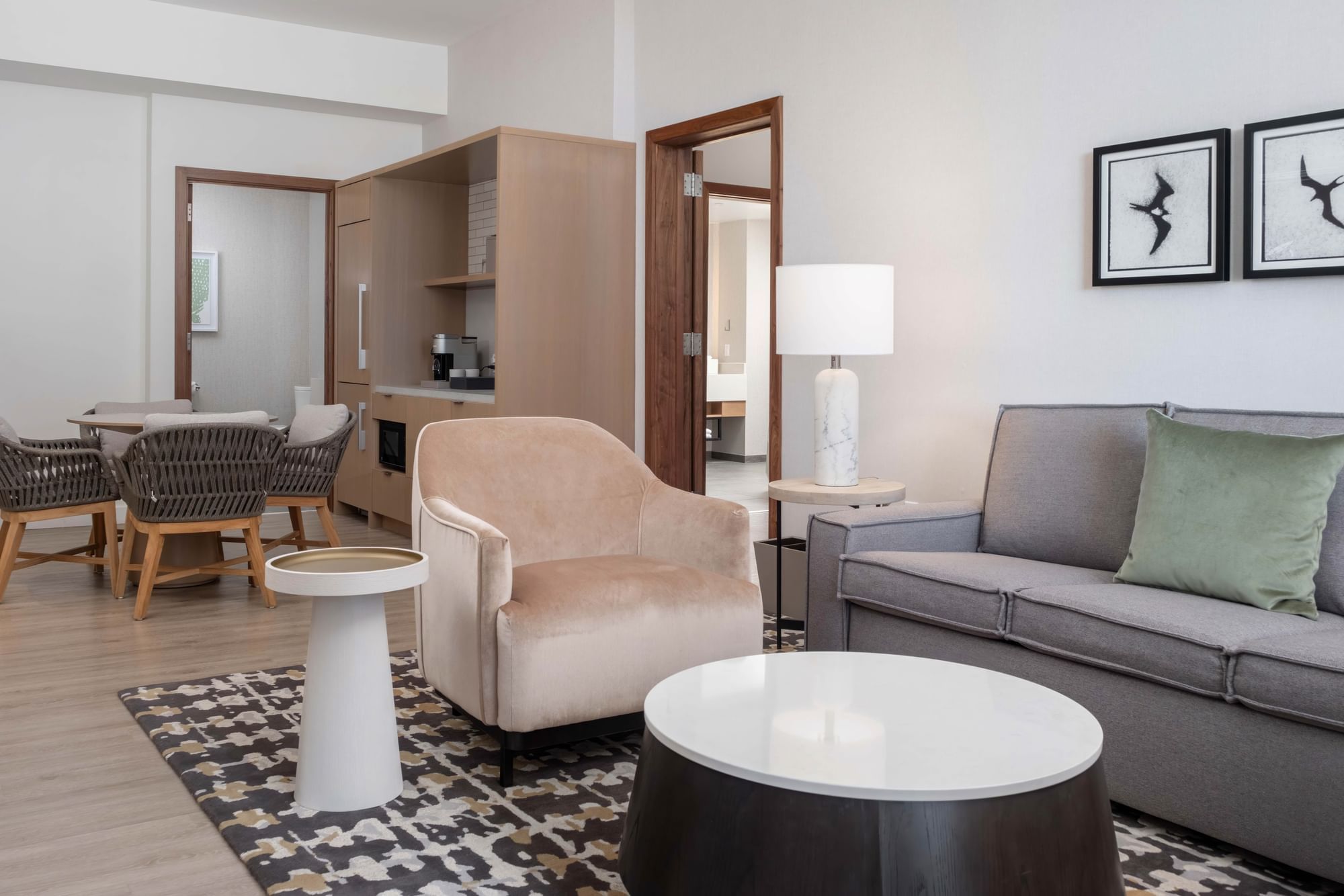 A wide view of a hotel suite's living area with a sofa, armchair, coffee table, and lamp.
