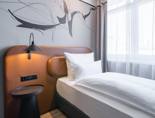 A single bed with a nightstand in the Classic Single Room at Titanic Comfort Kurfürstendamm