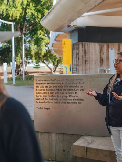 Tour guide standing next to a sign at BlackCard Cultural Toursnear Sofitel Brisbane Central