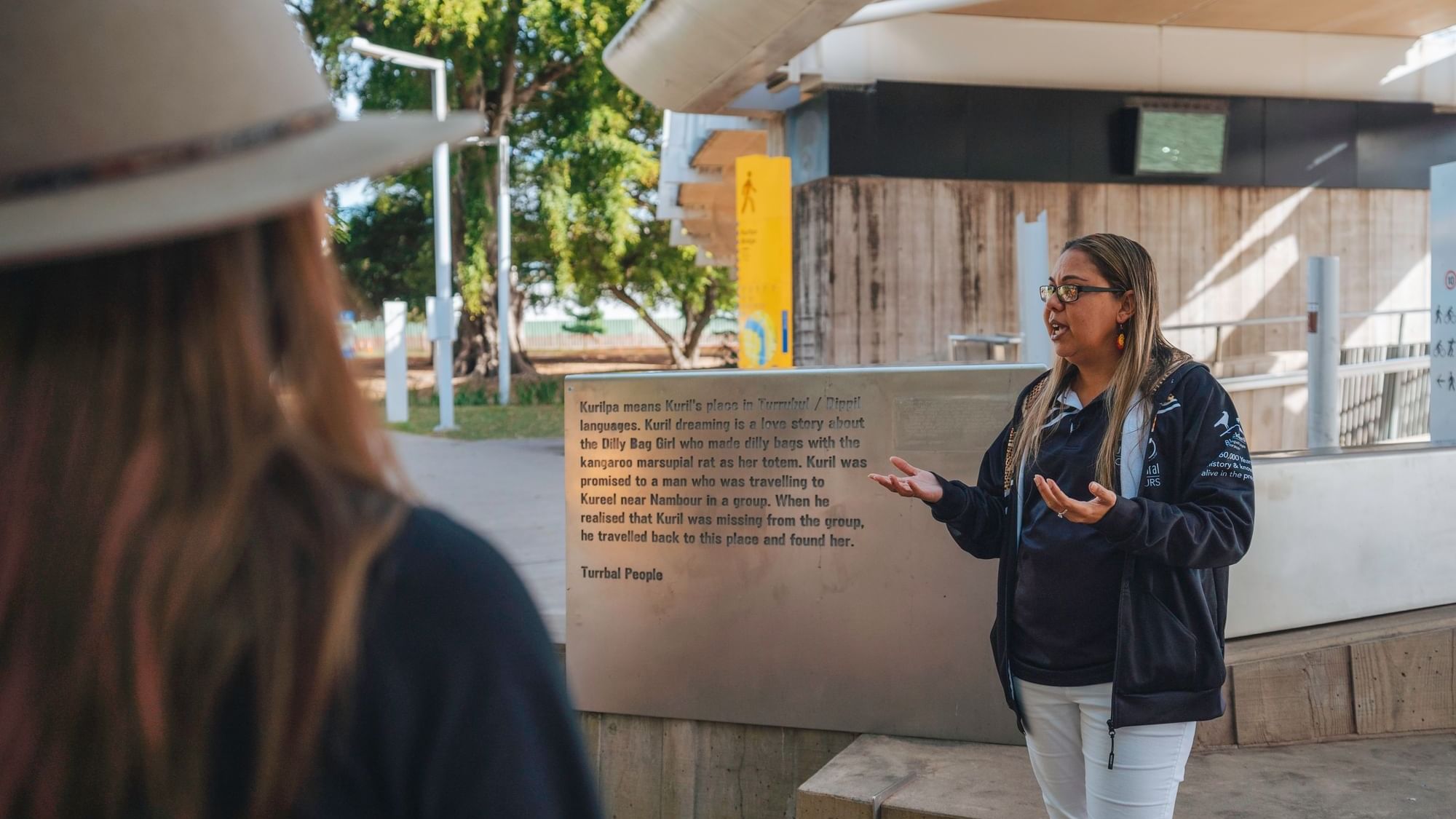Tour guide standing next to a sign at BlackCard Cultural Toursnear Sofitel Brisbane Central