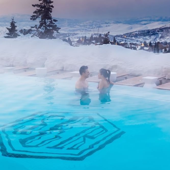 Couple enjoying a hot tub surrounded by snow at Stein Eriksen Residences