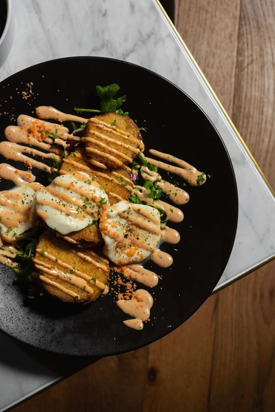 Black plate with golden fried patties drizzled with creamy sauce at Cypress & Oak, a steakhouse in Frankfort, KY