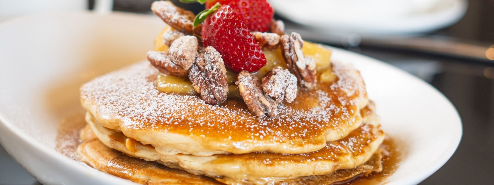 Pancakes with pecans and strawberries under powdered sugar in The Landmark - Breakfast at Warwick Melrose Dallas