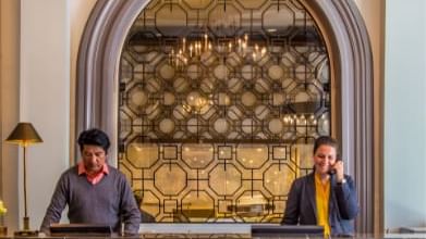 Two staff members stand by a dark marble desk in front of a geometric screen at Warwick Hotels and Resorts