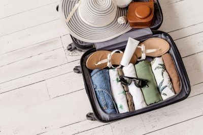 Luggage and suitcase packing for vacation on white wooden background in studio.