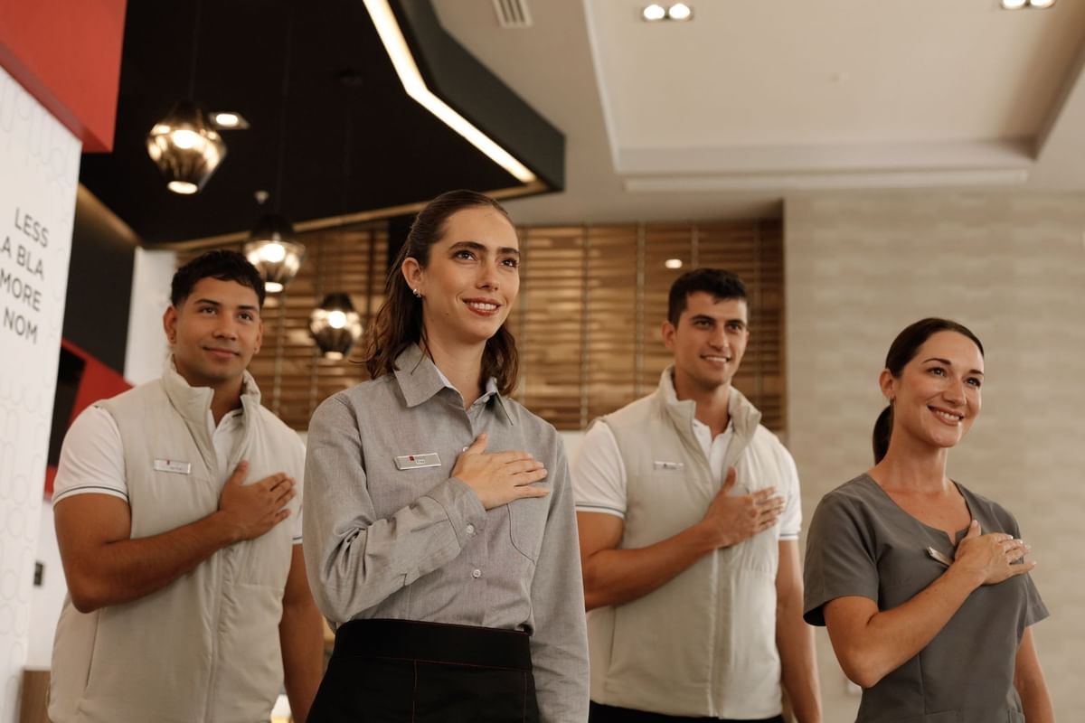Miembros del personal de pie con orgullo, mano en el corazón, en Fiesta Inn