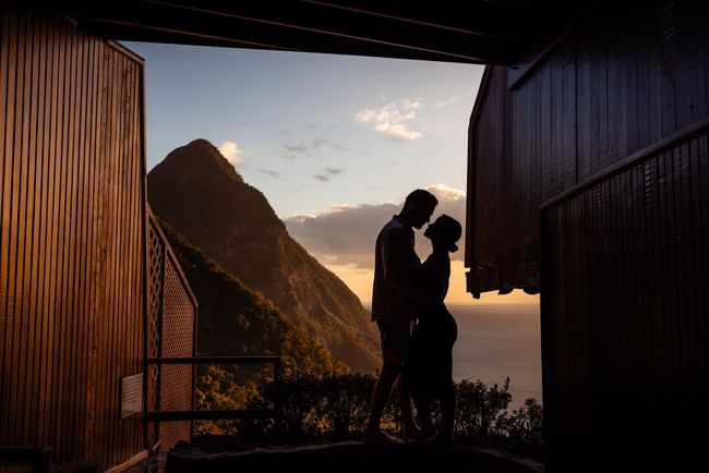 A couple holding hands with a mountain backdrop in sunset time at Ladera Resort, Saint Lucia