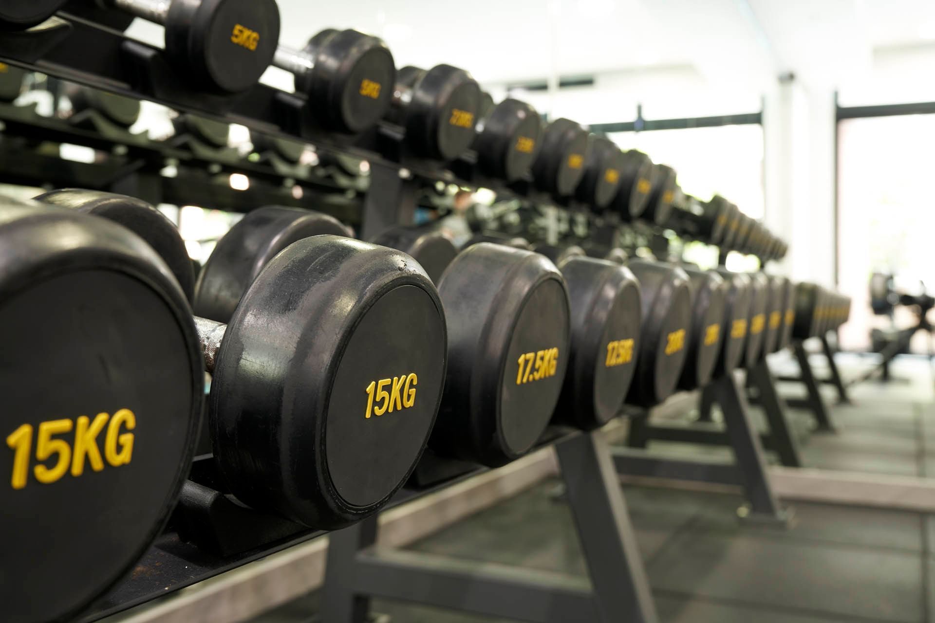 A neat row of black kilogram-labelled dumbbells on a rack in the modern gym at Orchard Grand Court