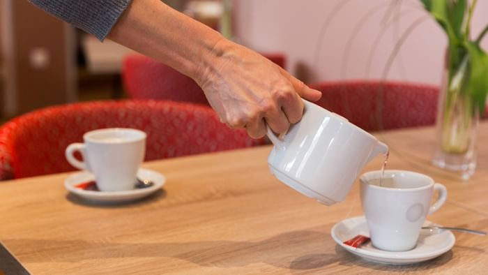 A maid pouring tea into a cup at Hotel alize