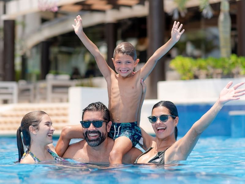 A family playing in the pool at The Reef Playacar
