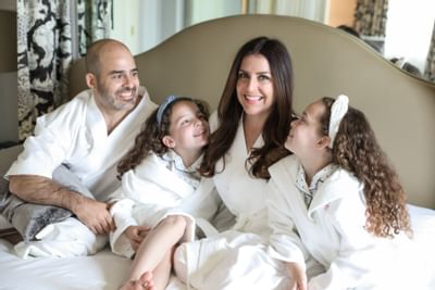 A family in bathrobes posing on a bed in a room at Eliot Hotel