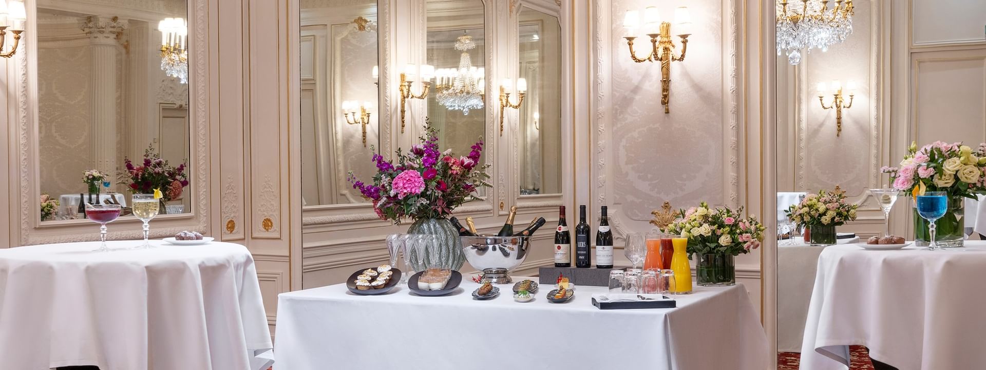 Catering setup, with wine & food placed by flowers under chandelier in Capucines Meeting Room at Hotel Westminster Paris