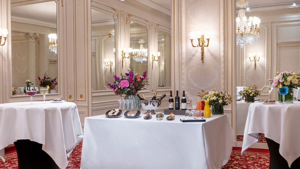 Catering setup, with wine & food placed by flowers under chandelier in Capucines Meeting Room at Hotel Westminster Paris
