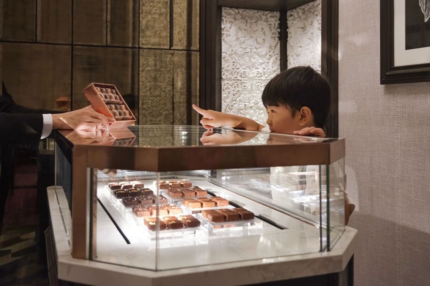 Child admiring chocolates as staff offers a treat box in Chocolaterie at Park Hyatt Saigon