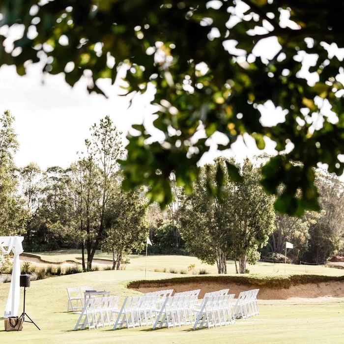 Outdoor wedding setup with chairs and an arch on a golf course at Mercure Kooindah Waters