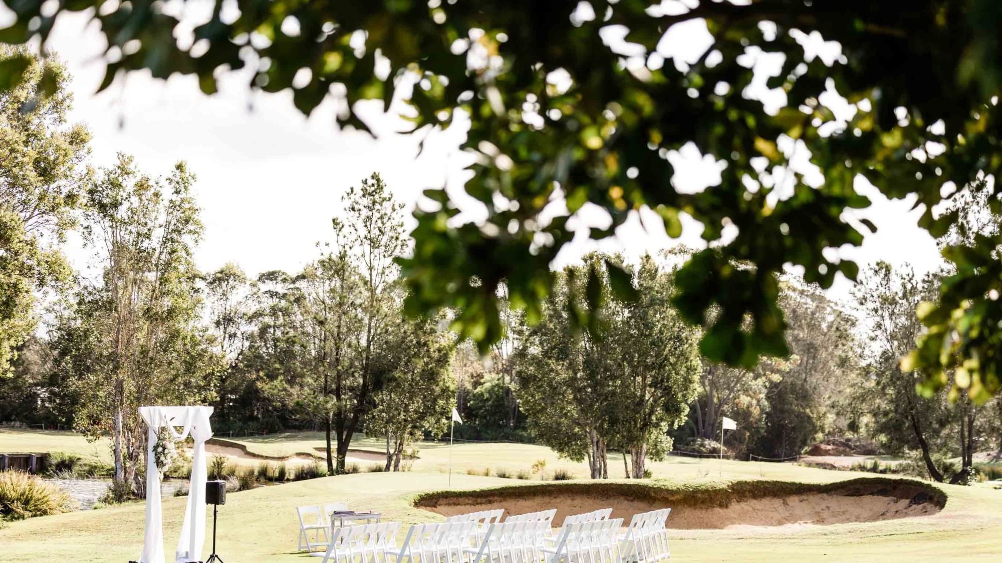 Outdoor wedding setup with chairs and an arch on a golf course at Mercure Kooindah Waters