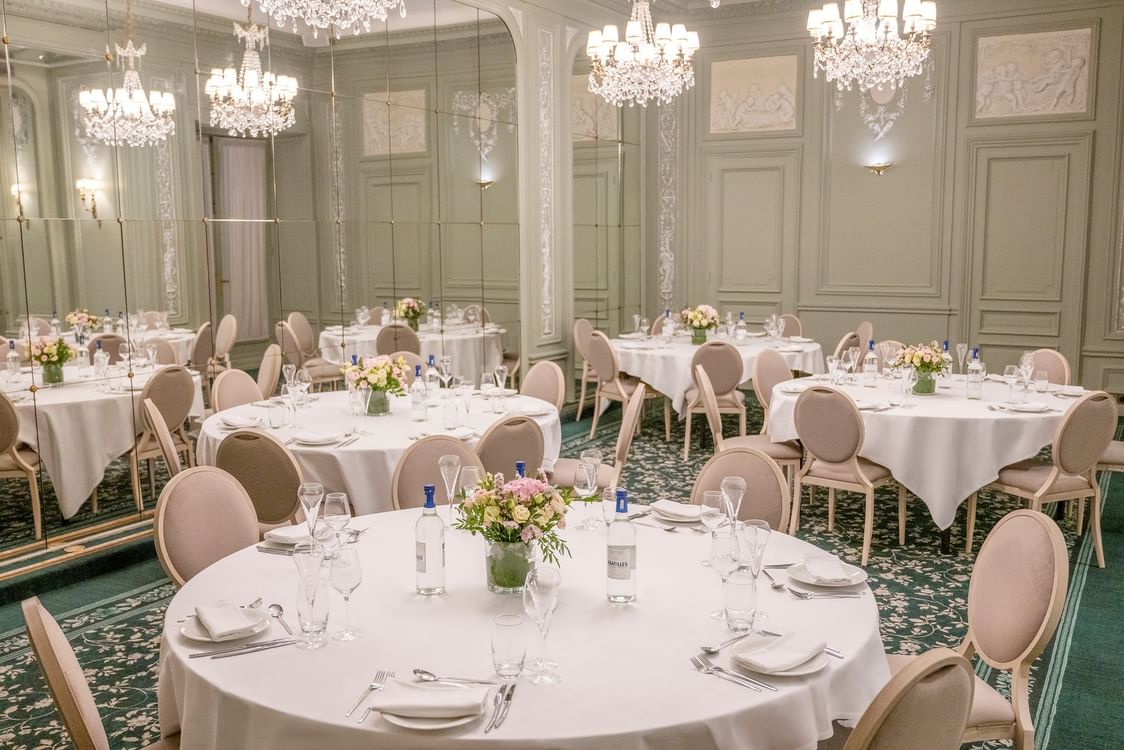 Salle de réception élégante avec tables rondes, lustres en cristal et murs ornés de moulures à Hotel Westminster Warwick Paris