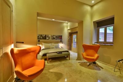 Seating area and ottoman by the bed in Terrace Suite with wall-mounted photographs at Billini Hotel Historic Luxury