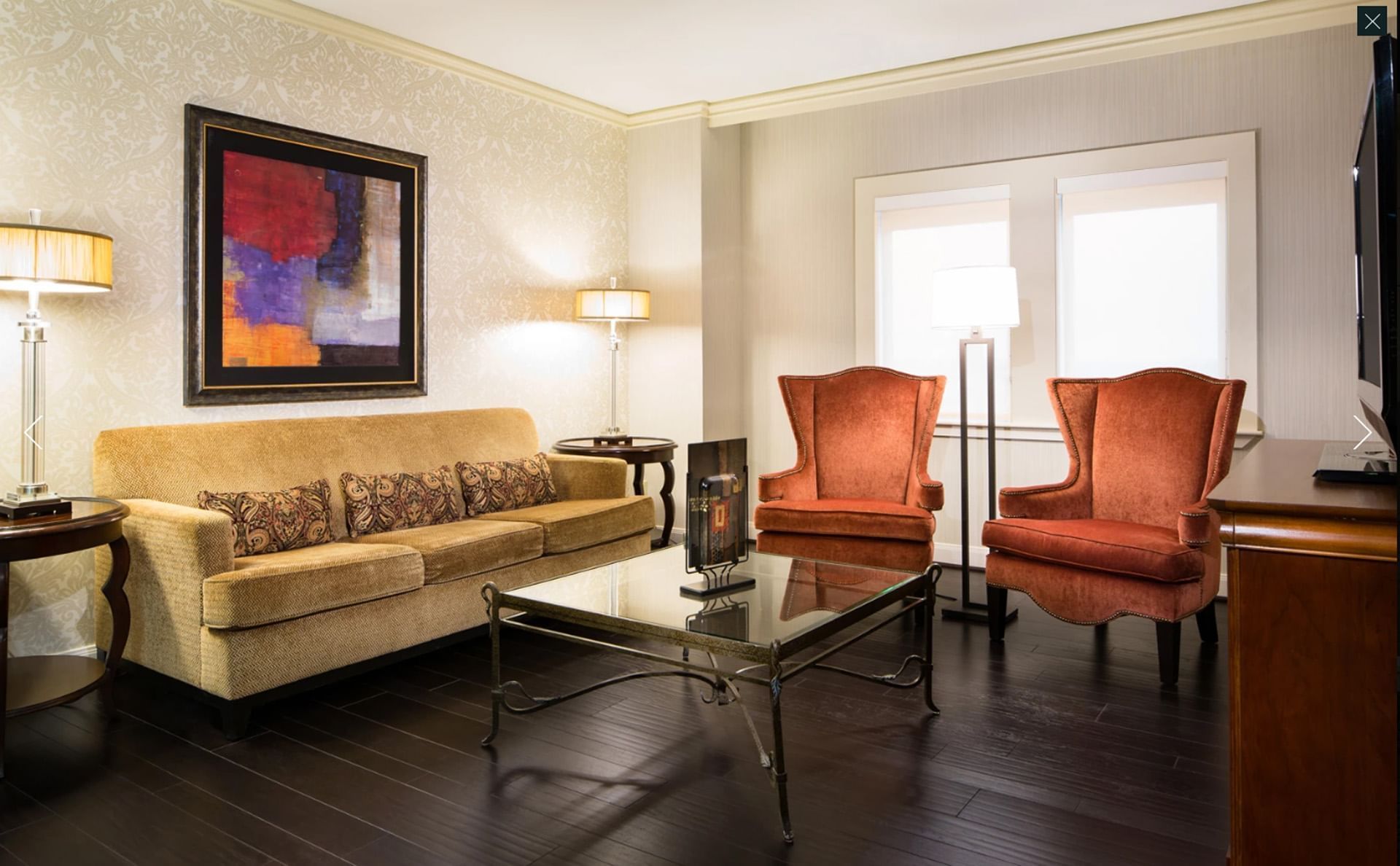 A hotel lobby lounge with a couch, two chairs, a coffee table, and a painting on the wall.