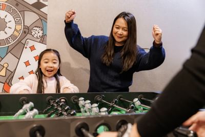 Mother and child playing happily on a foosball table, a fun family amenity in Charlottetown hotels at Rodd Royalty