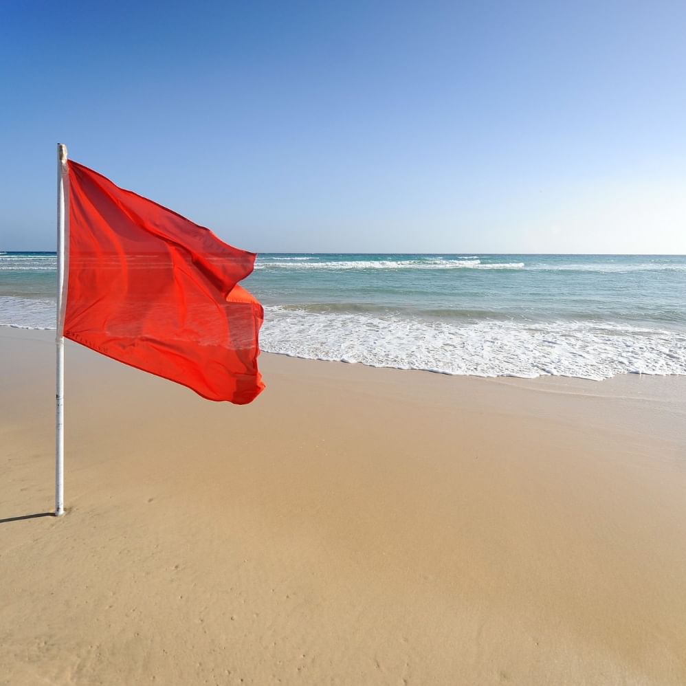 Karon Beach Phuket during the rainy season with red safety flag and waves in the Andaman Sea