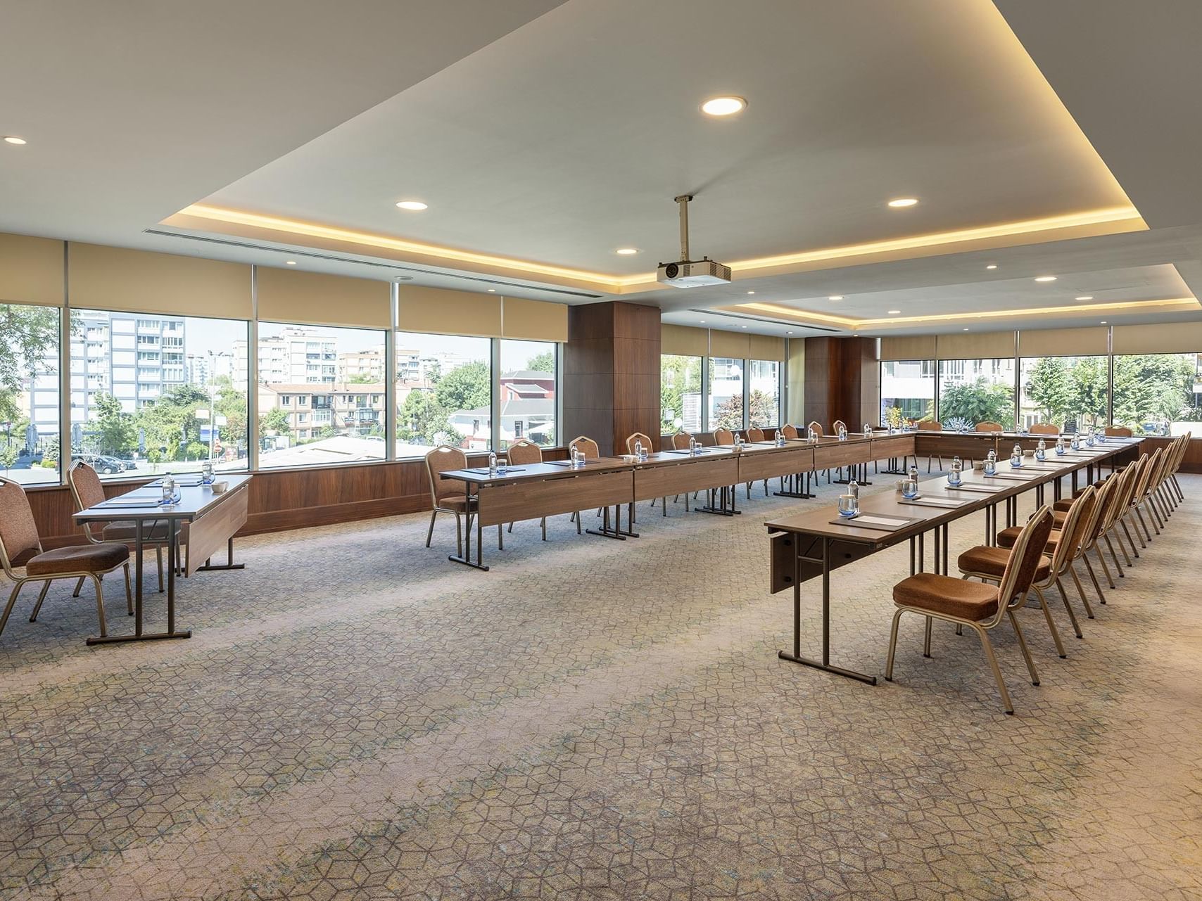 Atlantic Toplantı Salonu U şeklinde masa, sandalyeler ve şehir manzarasını gösteren geniş pencereler Titanic Port Bakırköy’de.