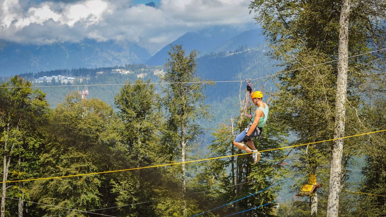 Person ziplining through a forest with mountain views in the background near Listel Whistler, a Coast Hotel