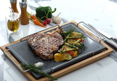 Grilled steak and colorful vegetables served on a slate platter in Park Lounge at Park Hyatt Saigon