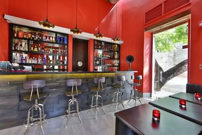 Bar interior with a sleek counter, illuminated shelves of liquor at Billini Hotel Historic Luxury