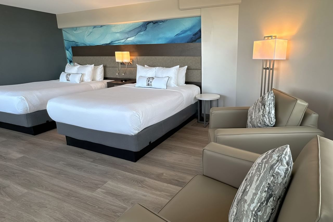 Hotel guestroom with two queen beds and two armchairs