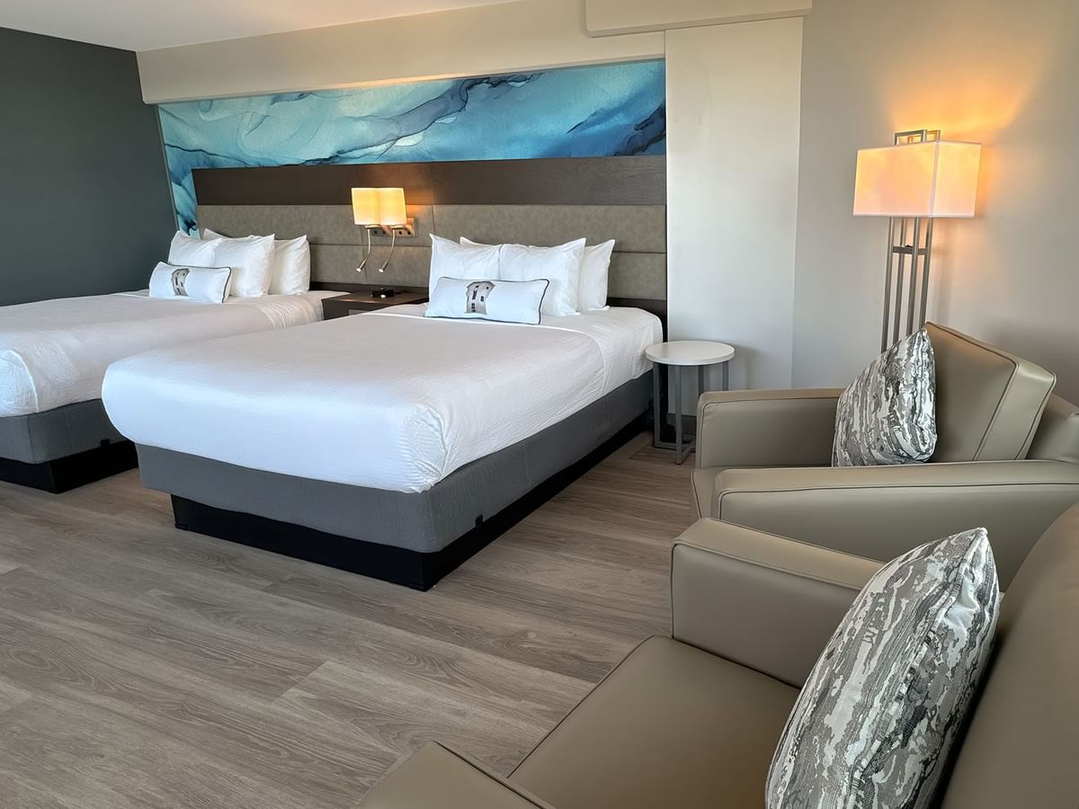Hotel guestroom with two queen beds and two armchairs
