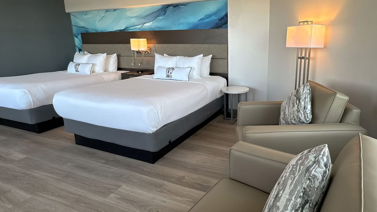 Hotel guestroom with two queen beds and two armchairs
