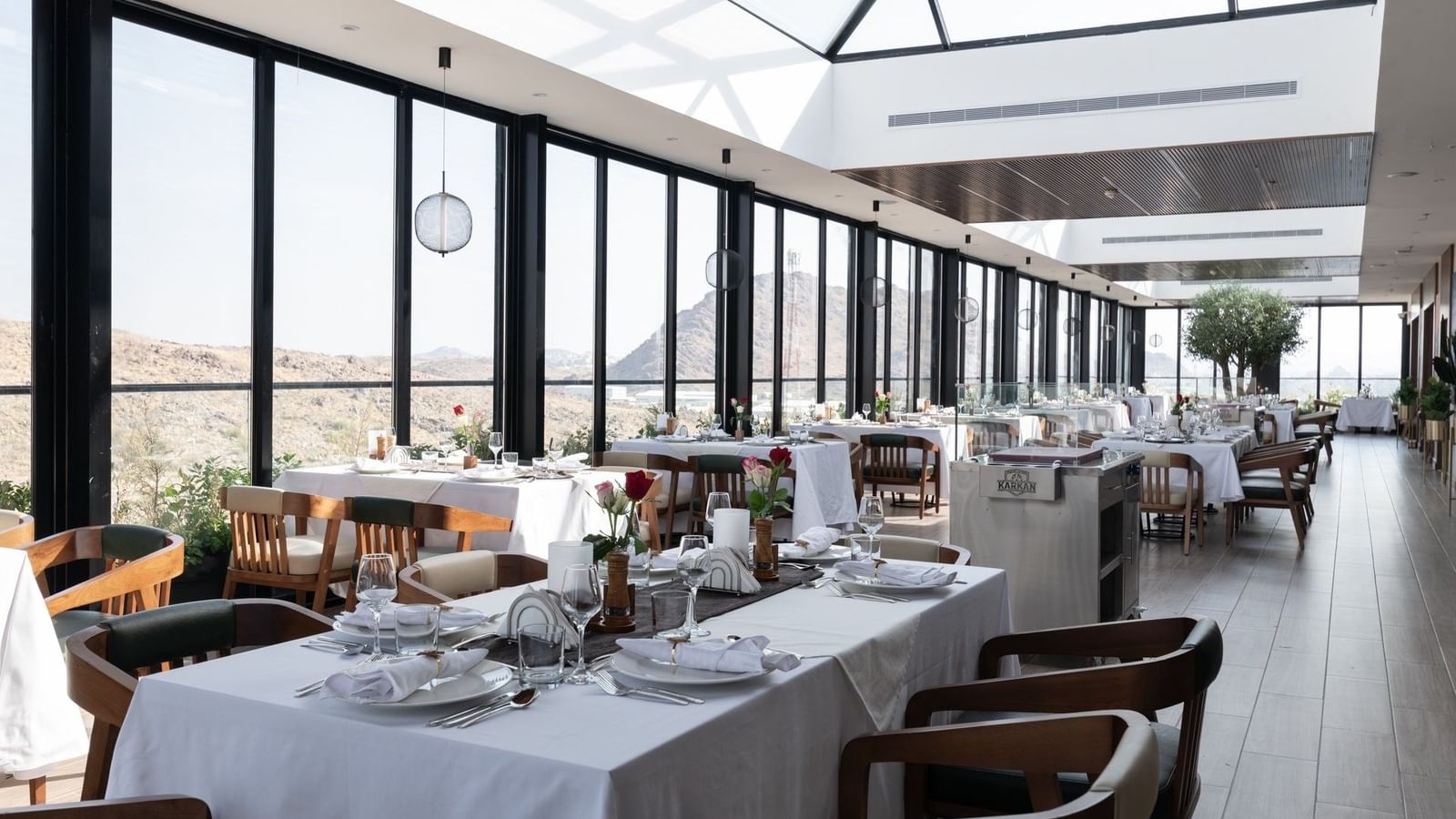 Dining sets by floor windows overlooking the scenic deck in Karkan Restaurant at Warwick Al Taif Hotel