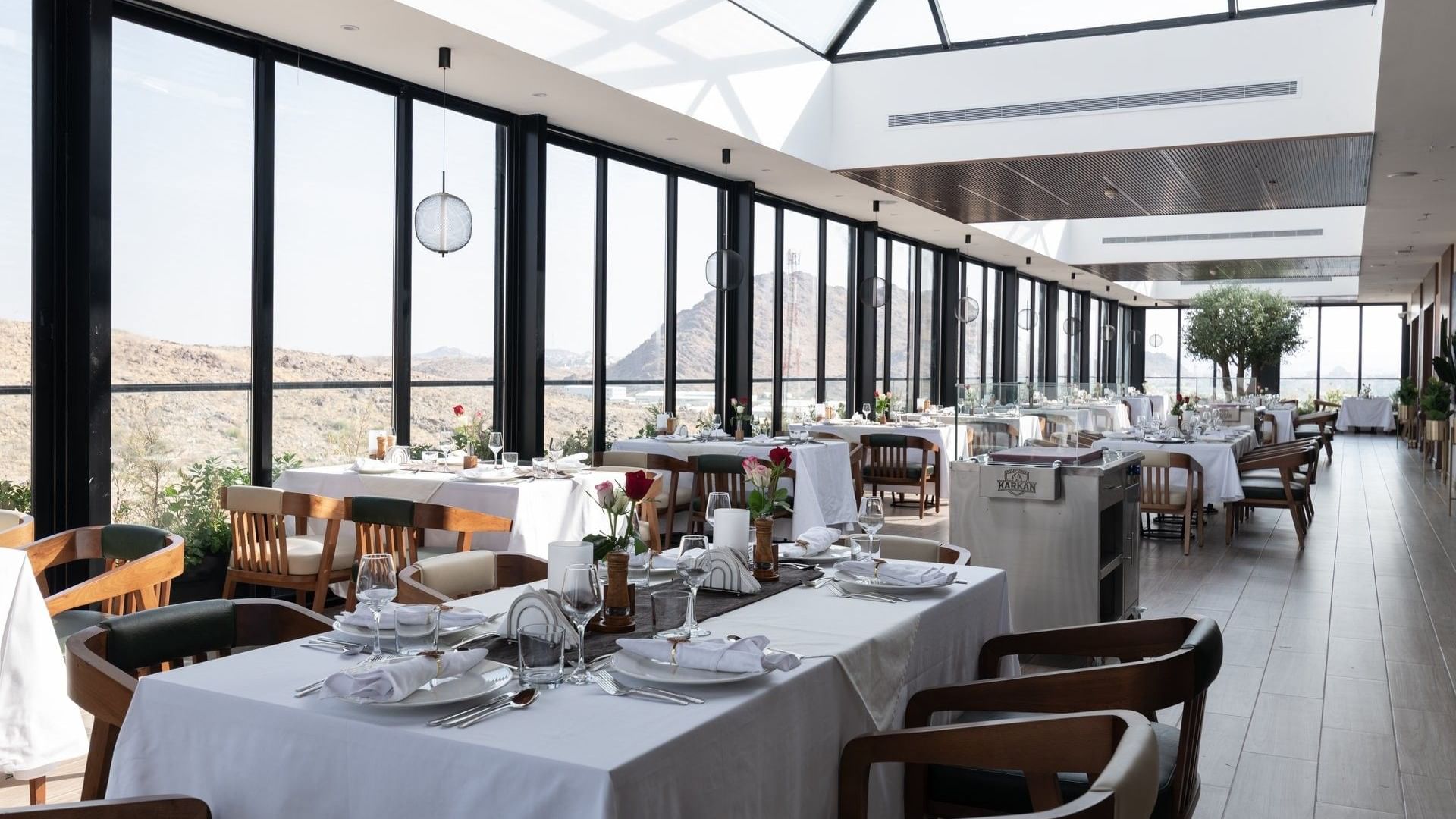 Dining sets by floor windows overlooking the scenic deck in Karkan Restaurant at Warwick Al Taif Hotel