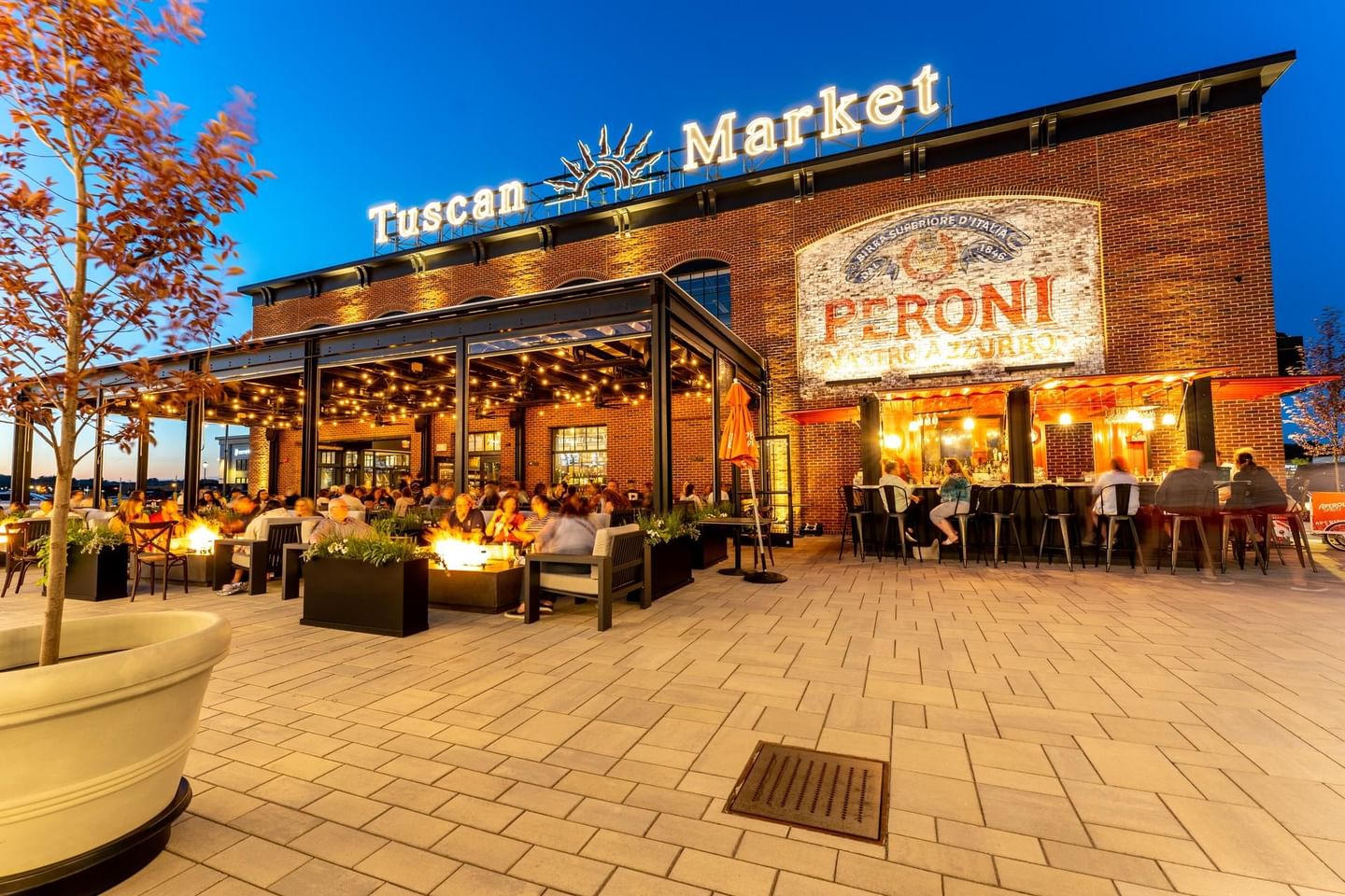 People hanging out in the patio area of illuminated Tuscan Market near The Artisan Hotel at Tuscan Village