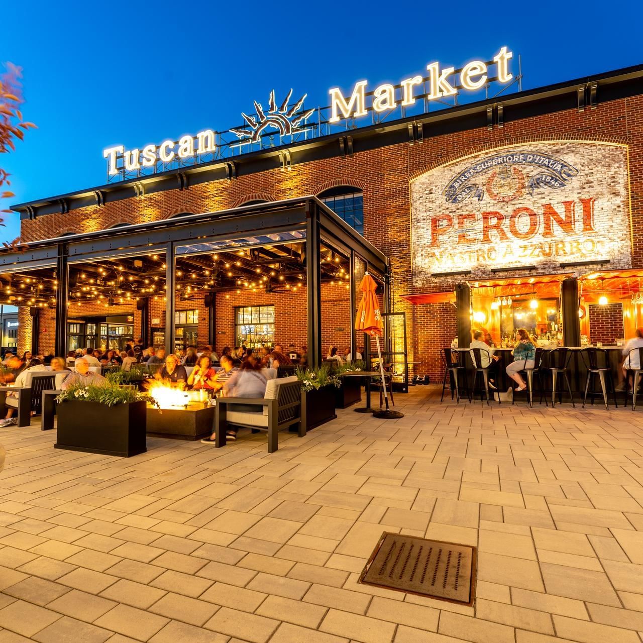 People lounging by the open space in illuminated Tuscan Market near The Artisan Hotel at Tuscan Village