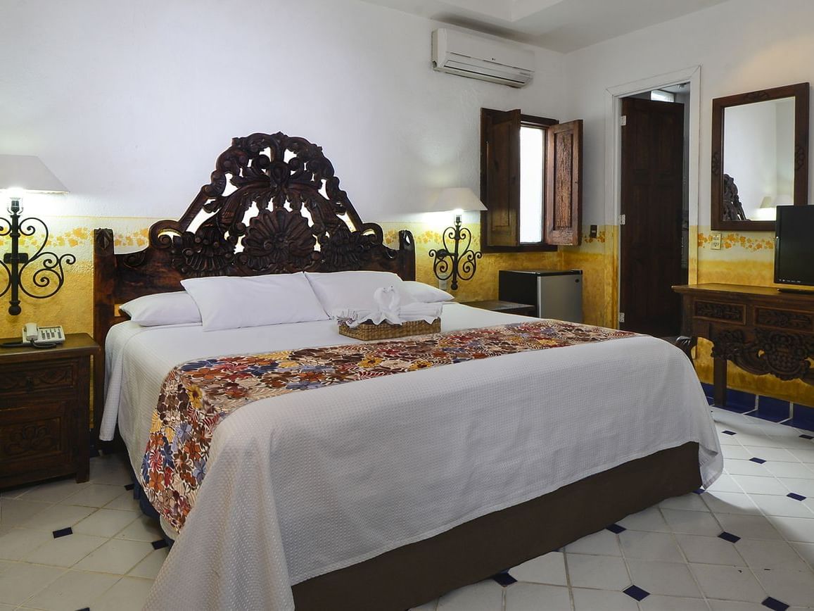 room with bed, small dressing table and yellow wallpaper