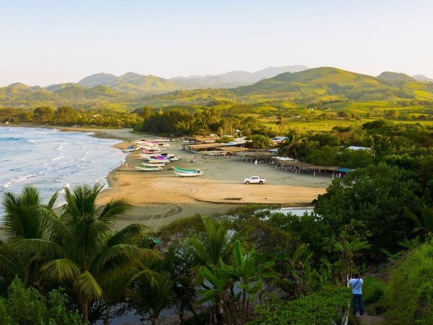 Playa Punta Roca Partida con botes blancos y colinas verdes al fondo cerca de Camino Real Hotels