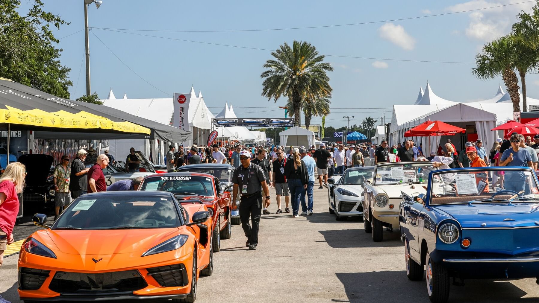 Crowd of people and classic cars displayed at Barrett-Jackson event.