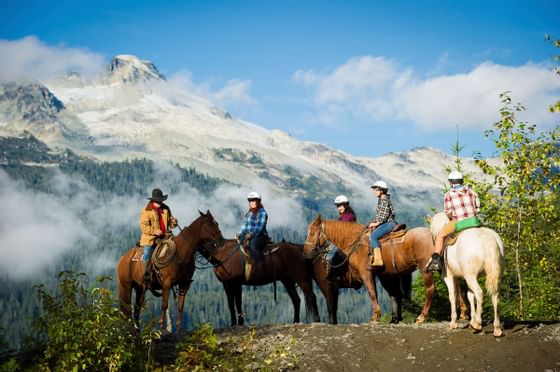 Group of people riding horses on a mountain trail near Blackcomb Springs Suites